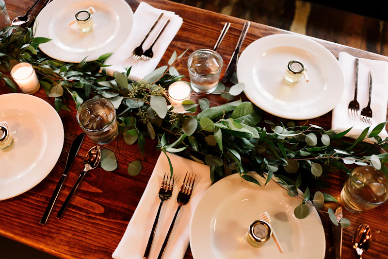Long wooden reception table with a eucalyptus garland runner and candlelight